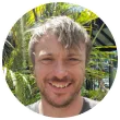 A man is smiling in a circle with trees in the background